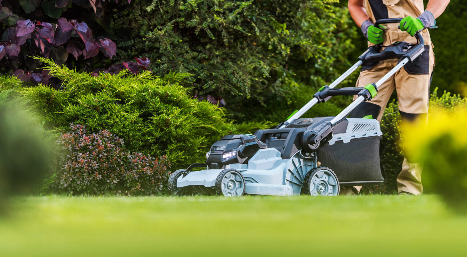 Professional lawn care technician mowing a well-maintained garden